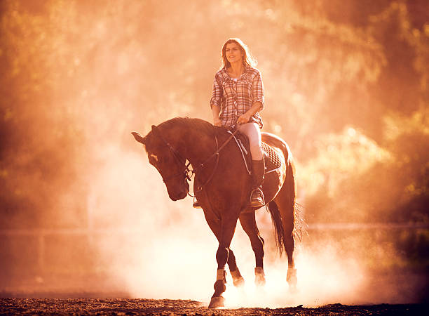 smiling young woman horseback riding at sunset. - smiling earth horse bildbanksfoton och bilder