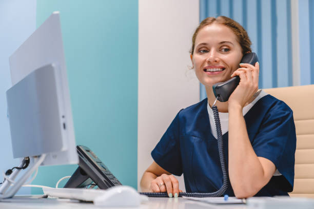 leende ung kvinna sjuksköterska receptionist talar på telefon medan du arbetar i modern klinik - happy scrubs nurse phone bildbanksfoton och bilder