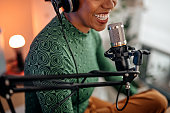 istock Smiling young woman recording podcast 1355368074