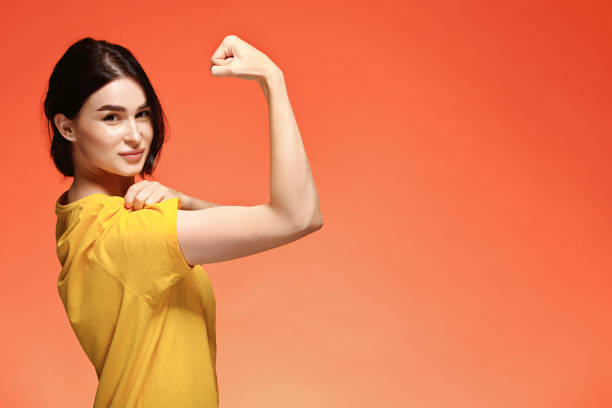Smiling young woman showing her bicep. Girl power concept stock photo