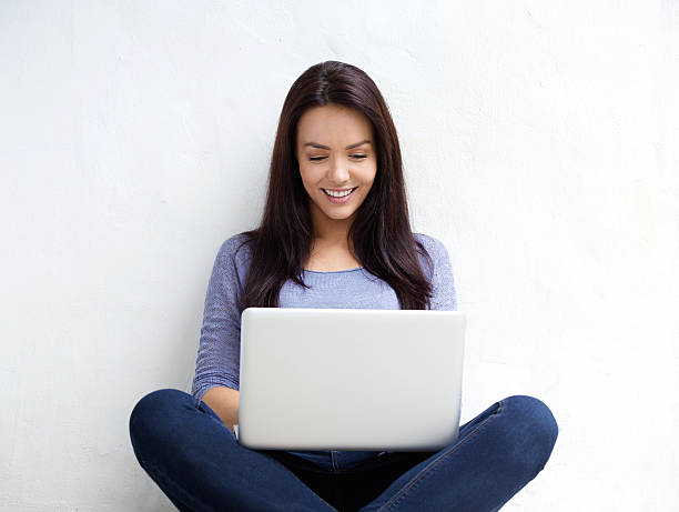Smiling young woman using laptop stock photo