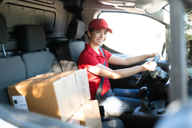 glimlachende jonge vrouw die als leveringsbestuurder werkt - koeriers stockfoto's en -beelden