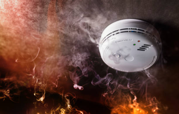 smoke detector and fire alarm in action background - rookmelder stockfoto's en -beelden