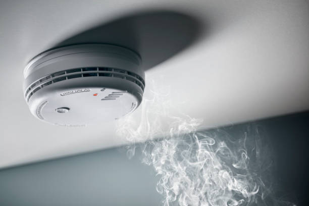 Smoke detector and interlinked fire alarm in action background stock photo