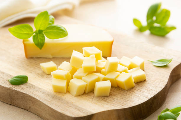 gerookte kaas op snijplank met basilicum, gesneden kaas - rokkaas stockfoto's en -beelden