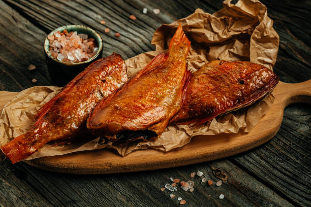 smoked fish on wooden cutting board. river bass fish smoked or salted. delicious snacks for beer - oily fish 個照片及圖片檔