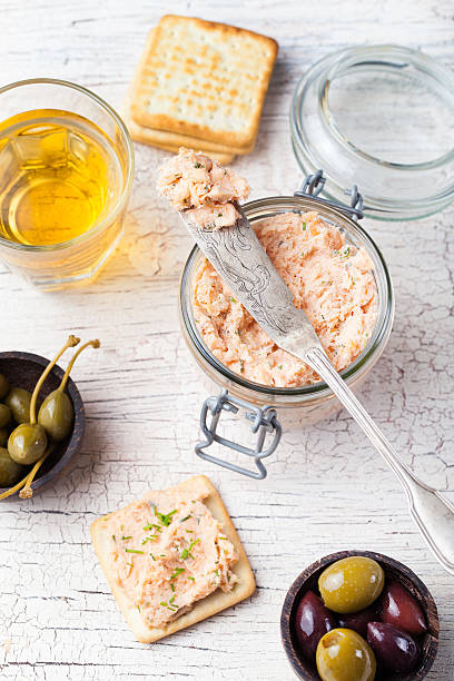 Smoked salmon and soft cheese spread, mousse Smoked salmon and soft cheese spread, mousse, pate in a jar with crackers, olives and capers on a wooden background pate stock pictures, royalty-free photos & images