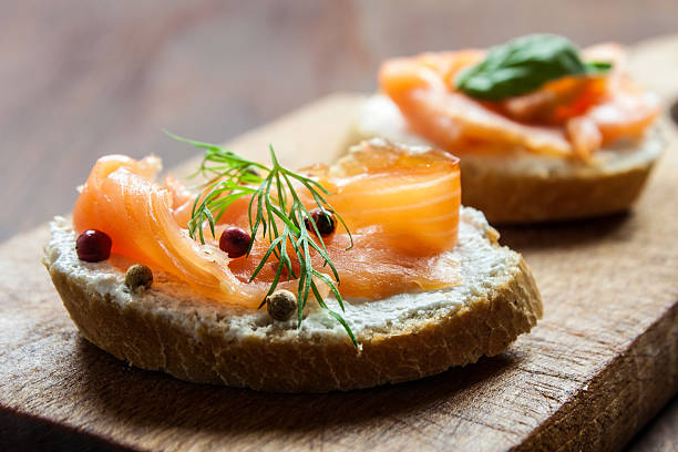 Smoked salmon canapes on a brown wooden plate stock photo