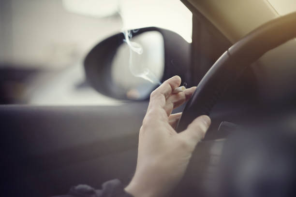 Smoking cigarettes while driving Smoking cigarettes at the wheel while driving a car. torpedo weapon stock pictures, royalty-free photos & images