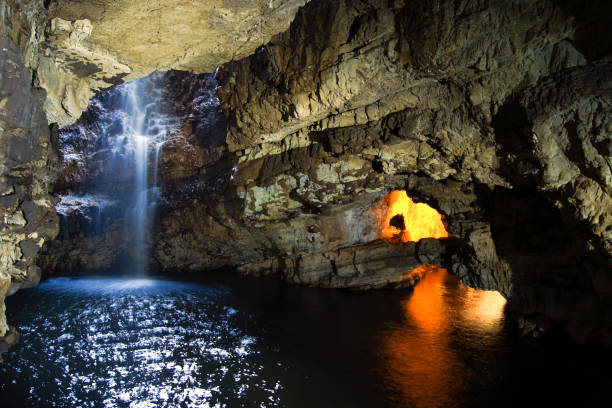Smoo Cave with waterfall in Durness, Scotland The inside of the Smoo Cave in the Scottish Highlands with illumination caithness stock pictures, royalty-free photos & images