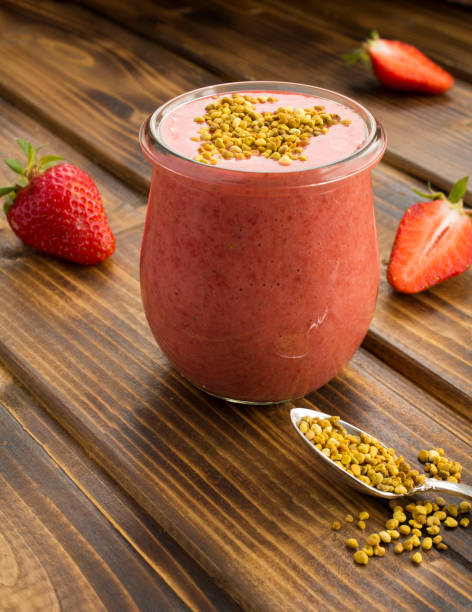 Smoothie with strawberry  and  bee pollen in the small glass jar on the brown  wooden background. Close-up. stock photo
