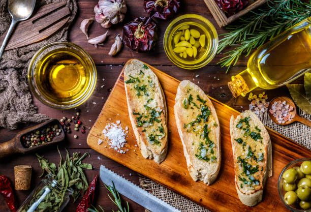 Snack or appetizer of garlic basil and olive oil bruschetta on table in a rustic kitchen Snack or appetizer of garlic basil and olive oil bruschetta on table in a rustic kitchen. Directly above view. garlic bread stock pictures, royalty-free photos & images