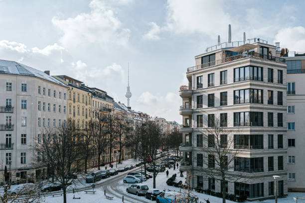 sneeuw afgetopte straat in berlijn prenzlauer berg met nieuwe woonhuizen en tv-toren op achtergrond - berlin snow stockfoto's en -beelden