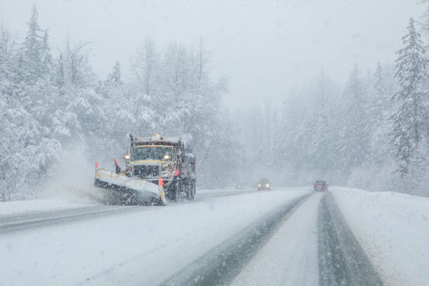 Snow plow clearing highway during snow storm. stock photo