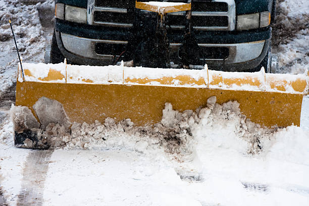 snow plow clearing parking lot during winter storm stock photo