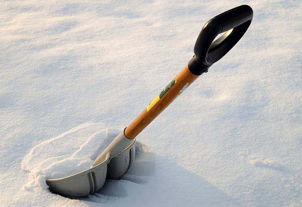 A gray plastic snow shovel in fresh snow after a winter storm.