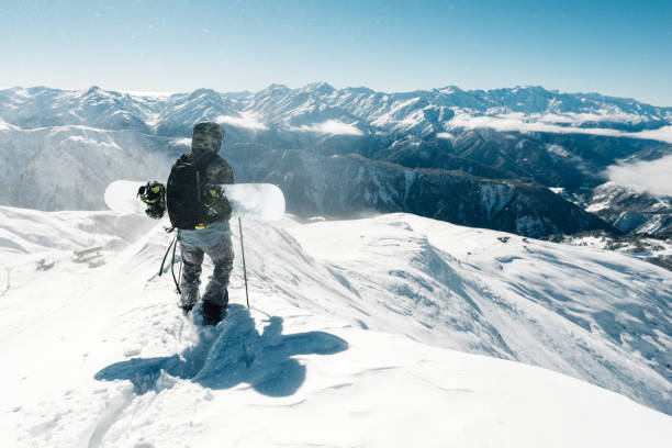 Snowboarder is standing with snowboard stock photo