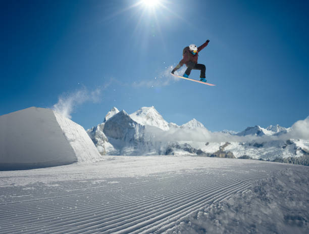 Snowboarder jumping in park stock photo