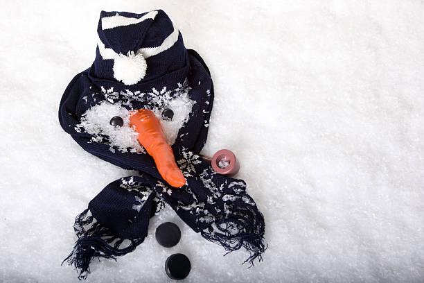 Snowman gear in the snow as if snowman melted Only the hat, scarf and carrot nose of this melted snowman remain in the snow. melting snow man stock pictures, royalty-free photos & images