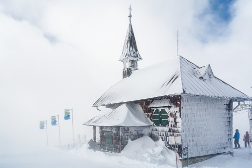 Snowy and cloudy view of chapel at mountains near Zell am See, Austria.