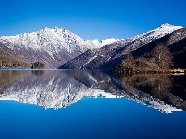Snowy mountaintops reflected in a clear blue lake stock photo