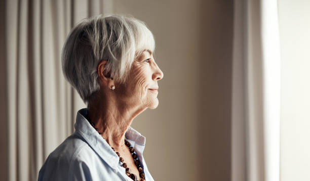 So many memories to look back on... Cropped shot of a senior woman looking out the window at home memory loss stock pictures, royalty-free photos & images