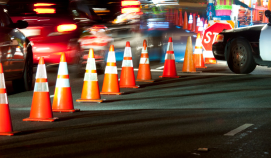 Vehicles passing along cones during nighttime DUI sobriety checkpoint