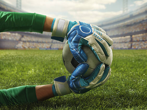 Soccer goalkeeper catches a ball Soccer goalkeeper catches a ball during a play on a professional soccer stadium. The stadium is blurred after him. A player is wearing unbranded soccer uniform. The stadium is made in 3D. goalie stock pictures, royalty-free photos & images