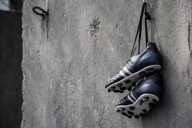 Soccer shoes hanging on a rough concrete wall. Soccer shoes hanging. equipación fútbol stock pictures, royalty-free photos & images