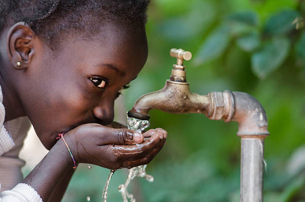 Social Issues: African Black Child Drinking Fresh Water From Tap stock photo