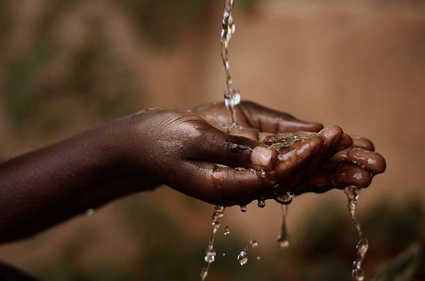 Social Issues: Water Pouring in African Child's Hands stock photo