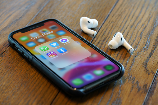 iPhone 11 Pro showing Social media applications on its screen with a pairs of AirPods Pro