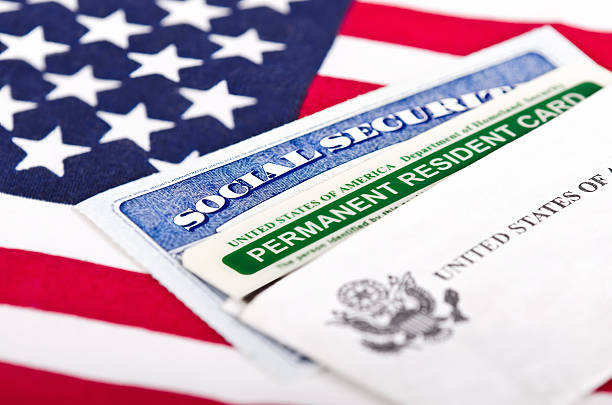 Social Security card and permanent resident on USA flag United States of America social security and green card with US flag on the background. Immigration concept. Closeup with shallow depth of field. emigration and immigration photos stock pictures, royalty-free photos & images