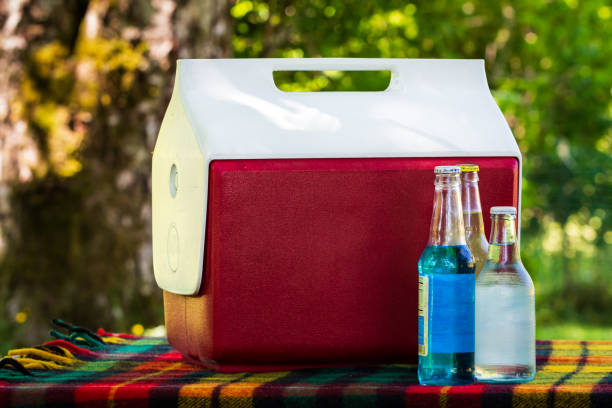 Soda and Bottled Water in front of vintage cooler on a park picnic bench stock photo