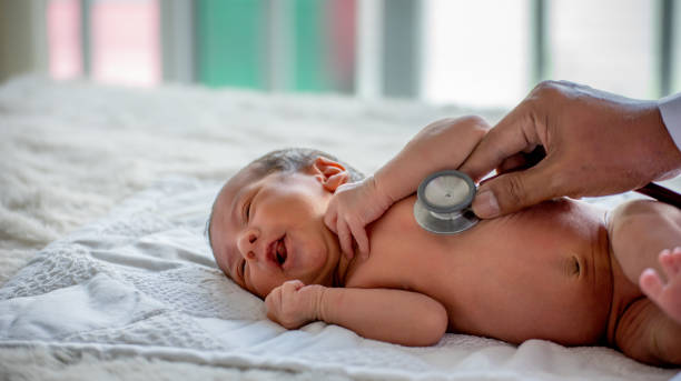 zachte vervaging van de handen van de dokter gebruik stethoscoop om de gezondheid van de pasgeboren baby te controleren en hem te verzorgen of de ziekte of aandoening te genezen - newborn stockfoto's en -beelden