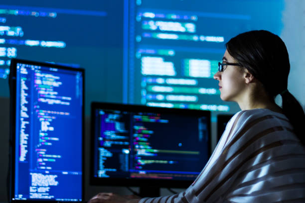 Software developer freelancer woman working at night Software developer freelancer woman female in glasses work with program code C++ Java Javascript on wide displays at night Develops new web desktop mobile application or framework Projector background it support stock pictures, royalty-free photos & images