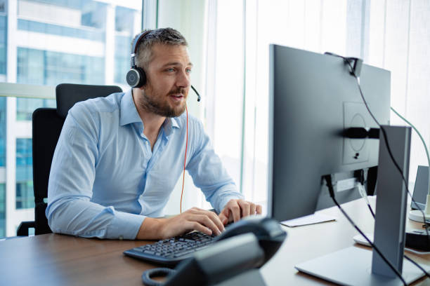 Software developer working on the computer, wearing headset stock photo
