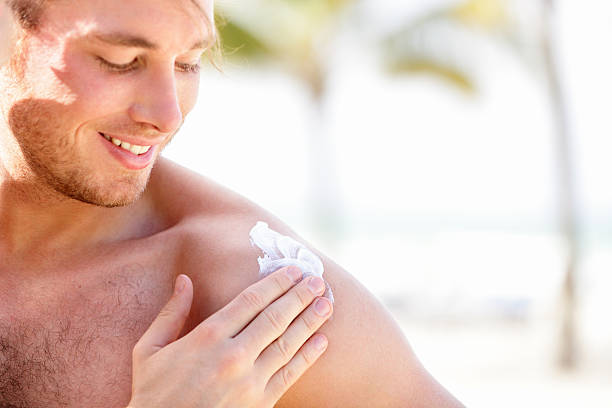 Solar cream / sunscreen Solar cream / sunscreen. Man putting sunblock sun screen cream on the beach under the sun during vacation on travel resort. Young caucasian male model. mens cream stock pictures, royalty-free photos & images