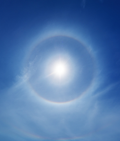 A prominent 22 degree solar halo surrounds the Sun.