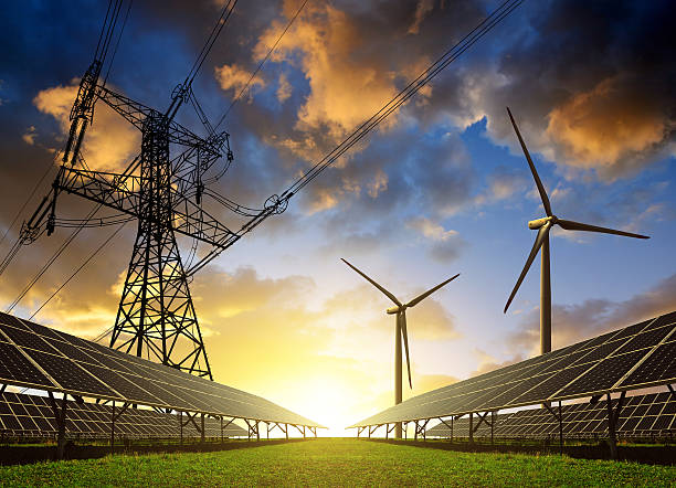 los paneles solares con turbinas eólicas y la torre de conducción eléctrica en sunset. - energía renovable fotografías e imágenes de stock