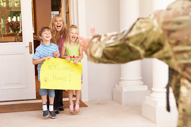Soldier being greeted by their family as they return home Soldier Returning Home And Greeted By Family With Welcome Home Sign soldiers returning home stock pictures, royalty-free photos & images