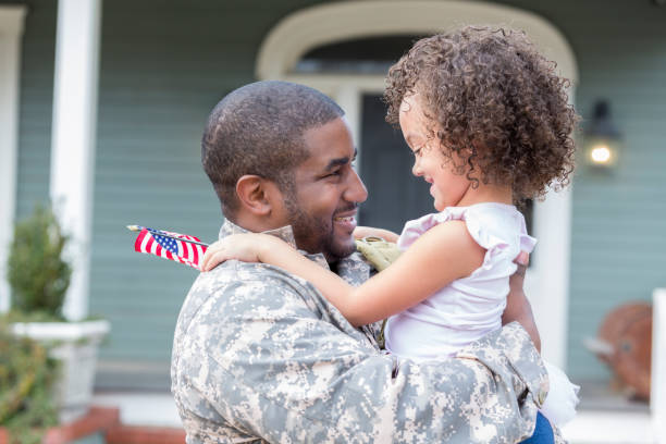 Soldier dad is reunited with adorable daughter Excited military dad picks up his adorable little girl upon his return home from deployment. They are standing in front of their home. veterans returning home stock pictures, royalty-free photos & images