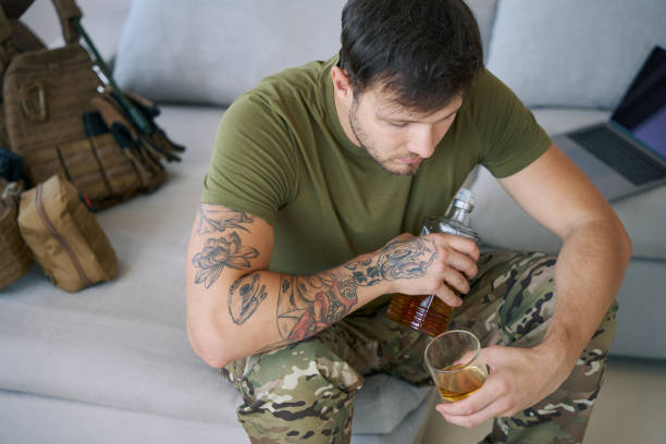 Soldier drinking whisky alone in living room stock photo