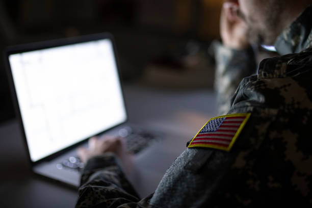 Soldier in military uniform typing on a computer. Focus on USA flag. Soldier in military uniform typing on a computer. Focus on USA flag. military base stock pictures, royalty-free photos & images