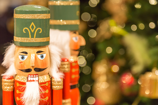 Soldier nutcracker statues standing in front of decorated Christmas tree with bokeh lights