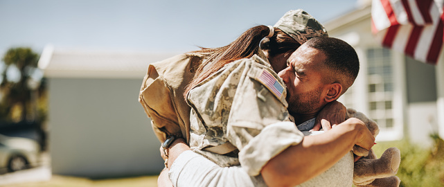 Female soldier embracing her husband after returning home from the army. American servicewoman having an emotional reunion with her husband after serving her country in the military.