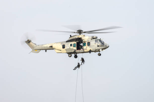 Soldier using rope going down to attack from military helicopter. Soldier using rope going down to attack from military helicopter. military helicopter stock pictures, royalty-free photos & images
