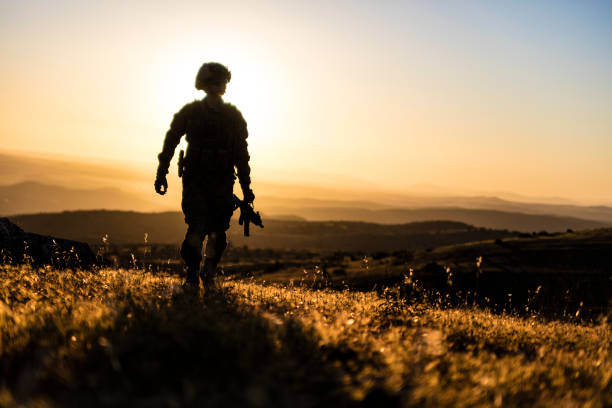 Soldier walking in battlefield at sunset stock photo