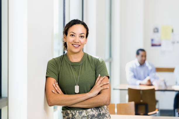 Soldier with arms crossed smiles for camera in workplace stock photo