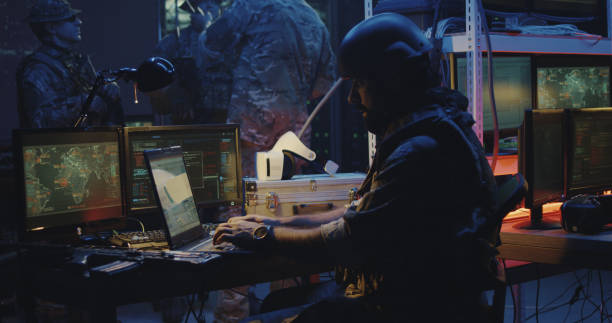 Soldier working on a laptop Medium shot of a soldier working on a laptop in full combat gear military base stock pictures, royalty-free photos & images